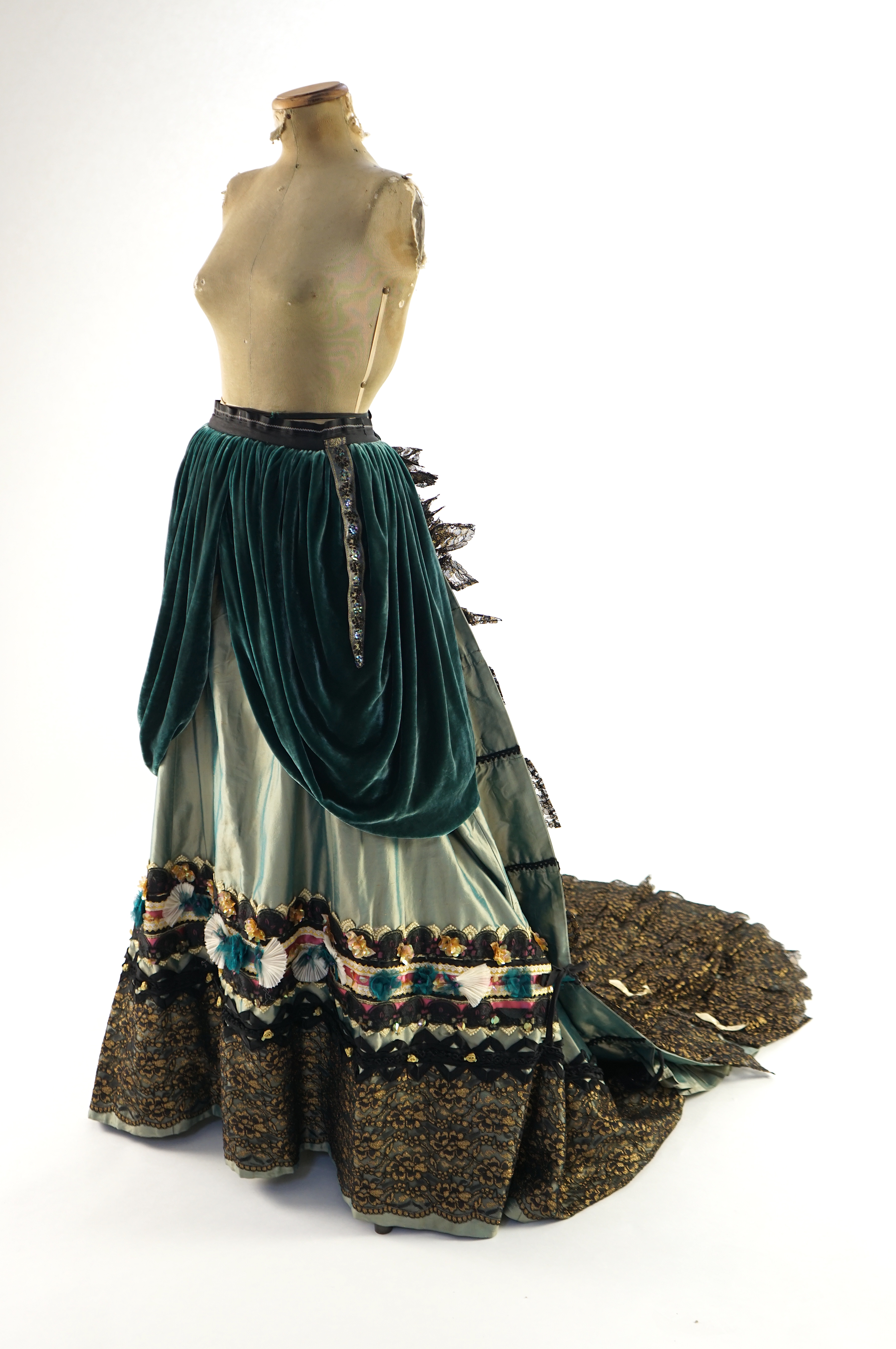 An Edwardian style lady's green taffeta skirt decorated with beaded, sequinned, ribboned border and swags of silk velvet, together with matching train layered with frilled black and gold lace, appliquéd with gold bows